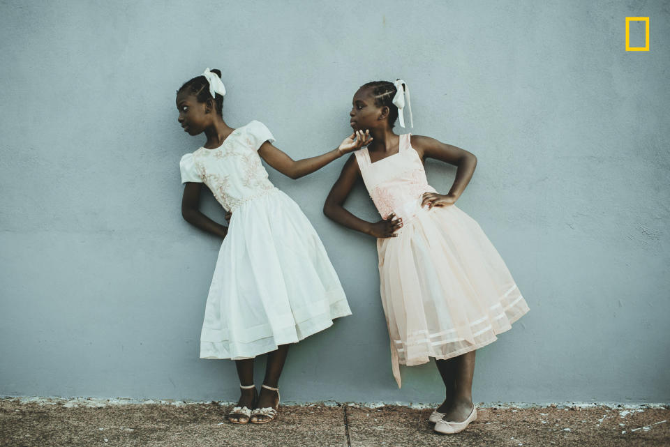 <strong>Second Place: "Le&iuml;da and La&euml;lle &mdash; I Will Lift You Up"<br /></strong><br />"Since 2016, I've been involved with Haitian immigrants and refugees living in my city, Estrela. I have become friends with some families, and especially with twin sisters, Le&iuml;da and La&euml;lle. They say living in Brazil is like living in paradise &mdash; very different from the reality of their country of origin. They dream of becoming models and teachers, as a way to earn money to bring their other relatives from Haiti to Brazil, to live all near one another. On this day, they were playing in front of their home, improvising exercises to develop their imagination and creativity, as if they were actresses, and playing an imitation game with poses. La&euml;lle reached for Le&iuml;da's face and lifted her head up, showing her where she should look. At this brief moment, I took the photo."