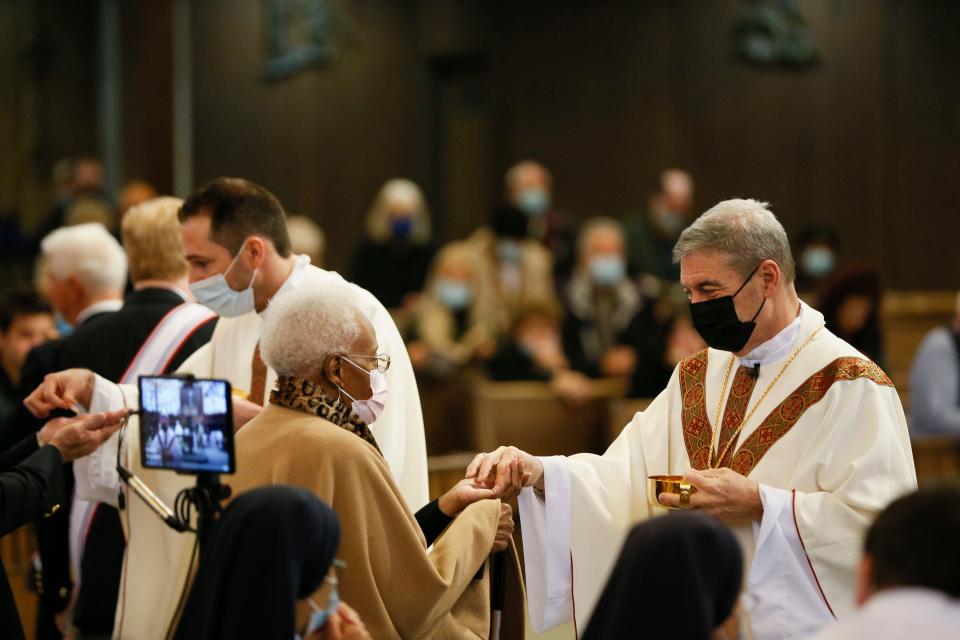 Father David Schalk, left, and Bishop Robert J Brennan, give out communion during one of Brennan’s last masses in Columbus at Christ the King Catholic Church in Columbus, Ohio, on Sunday, Nov. 21, 2021. Brennan was reassigned to be the new Bishop of Brooklyn.  It was also the 75th year anniversary of the church’s opening. 