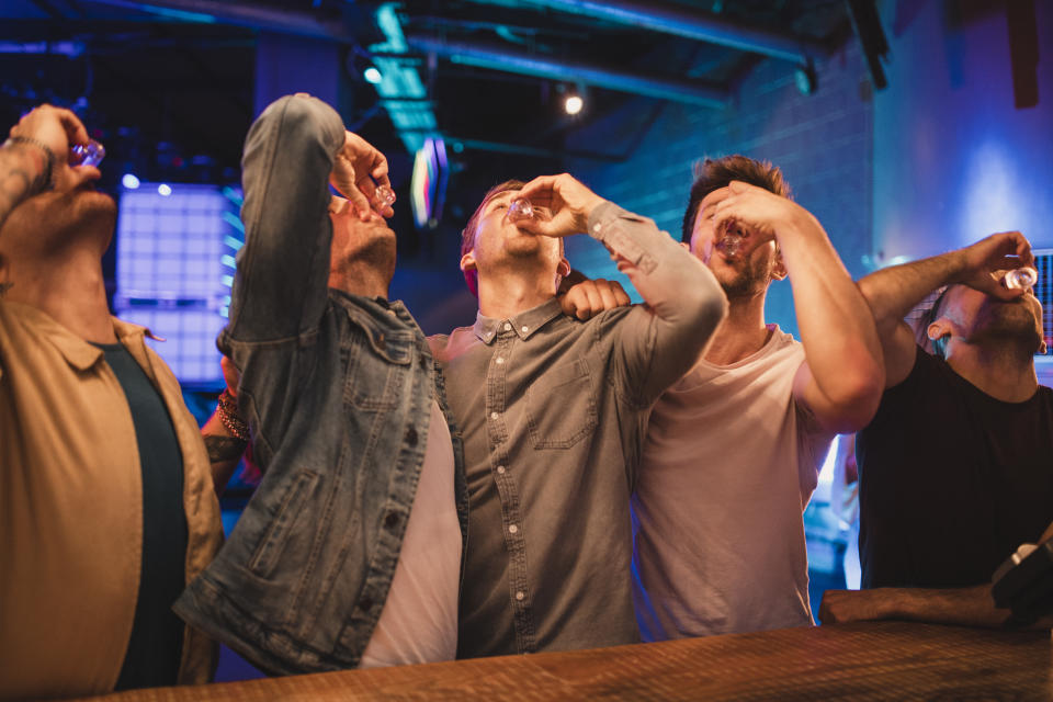 Group of male friends taking shots together on their night out.