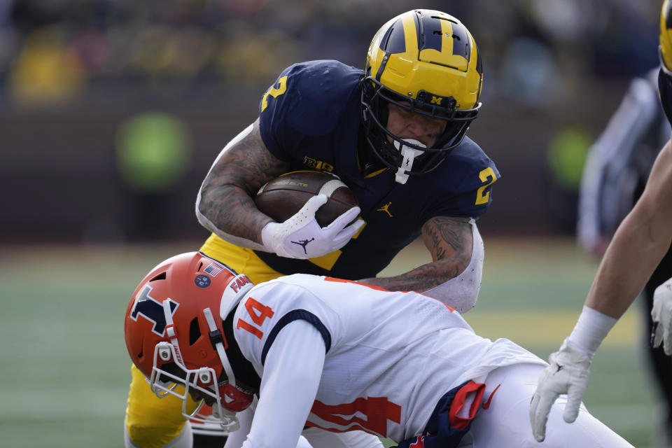 Michigan running back Blake Corum (2) runs the ball as Illinois defensive back Xavier Scott (14) defends in the first half of an NCAA college football game in Ann Arbor, Mich., Saturday, Nov. 19, 2022. (AP Photo/Paul Sancya)