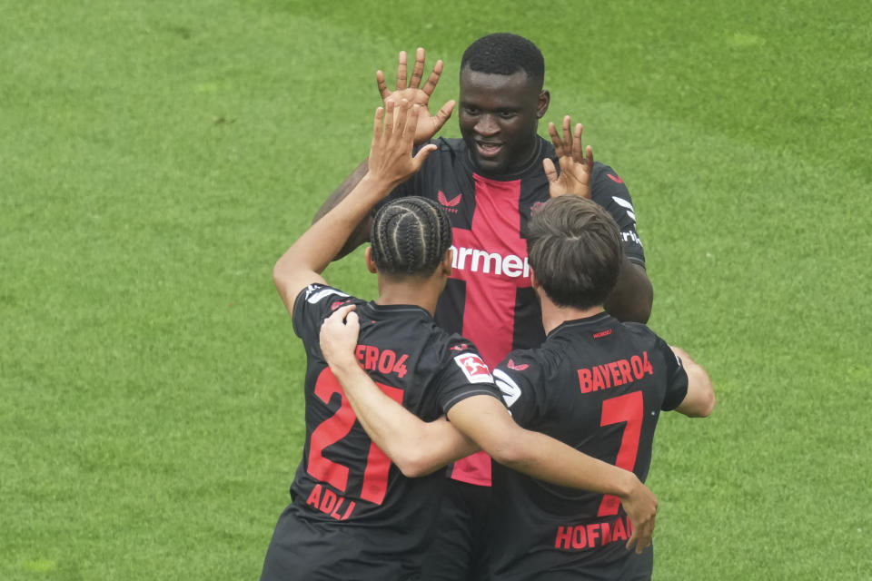 Leverkusen's Victor Boniface, top, celebrates with Amine Adli, left, and Jonas Hofmann after scoring the opening goal during the German Bundesliga soccer match between Bayer Leverkusen and FC Augsburg at the BayArena in Leverkusen, Germany, Saturday, May 18, 2024. Bayer Leverkusen have won the Bundesliga title for the first time. (AP Photo/Michael Probst)