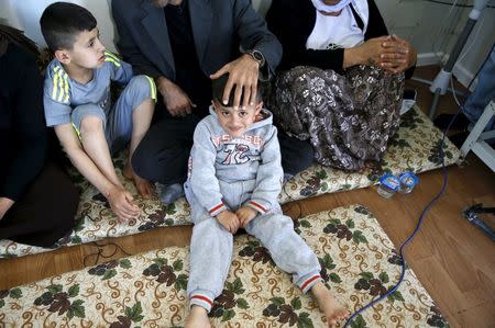 Freed Yazidi boy Murad (L), 9, who was trained by Islamic State, sits next to his five-year-old brother Emad, his parents, and his grandmother in their caravan at a refugee camp near the northern Iraqi city of Duhok April 19, 2016. REUTERS/Ahmed Jadallah