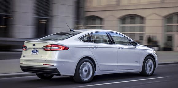 A rear three-quarter view of a white 2019 Ford Fusion Hybrid sedan; the changes are very subtle