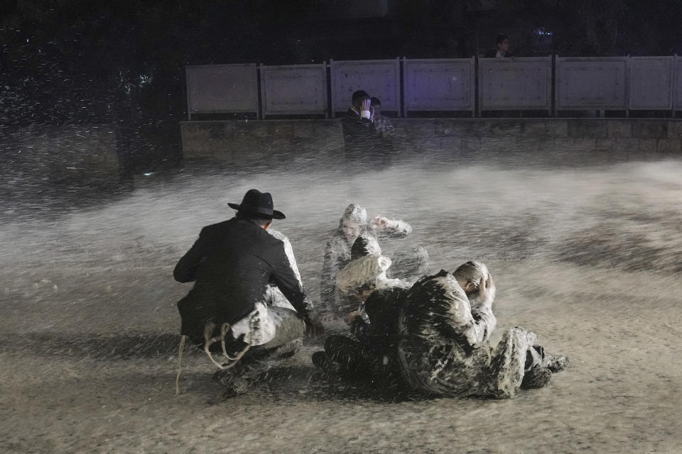 Ultra-Orthodox Jewish protesters are bathed in skunk-scented water launched by police during a protest against a Supreme Court order for them to begin enlisting for military service, in Jerusalem, June 30, 2024. (AP Photo/Mahmoud Illean)