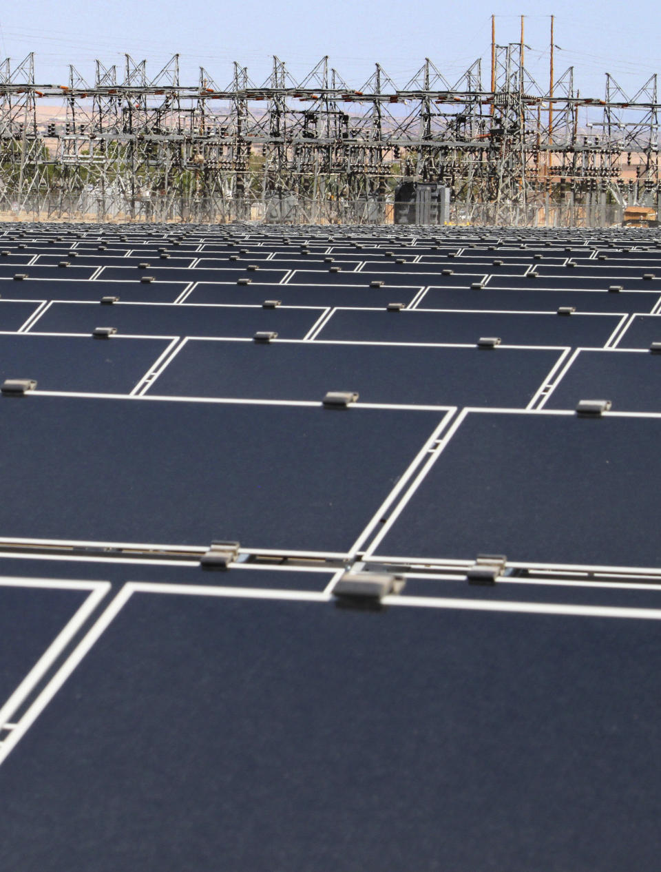 FILE - This April 20, 2011, file photo, shows dozens of rows of solar panels that make up Public Service Co. of New Mexico's 2-megawatt photovoltaic array in front of transmission lines near the utility's natural gas-fired generating station in Albuquerque, N.M. The federal government has finished another environmental review of a proposed transmission line that will carry wind-generated electricity from rural New Mexico to big cities in the West and similar reviews are planned for two more projects that would span parts of Utah and Nevada, the U.S. Interior Department announced Thursday, April 28, 2022. (AP Photo/Susan Montoya Bryan, File)