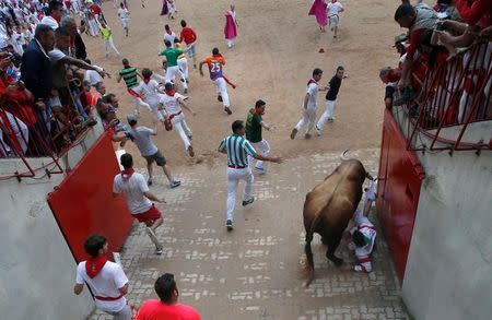 A runner is dragged on the horns of a Puerto de San Lorenzo bull at the entrance to the bullring, during the third running of the bulls at the San Fermin festival in Pamplona, Spain July 9, 2017. REUTERS/Joseba Etxaburu