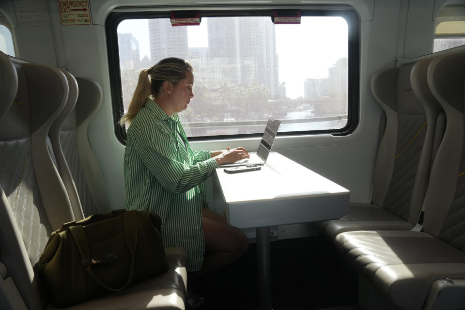 Kelly Mc Kenna, of N.Y., catches up on work while riding the Brighline train from West Palm Beach to Aventura to meet friends, Friday, Sept. 8, 2023, in Fort Lauderdale, Fla. Brightline, which began running its neon-yellow trains the 70 miles (112 kilometers) between Miami and West Palm Beach in 2018, is the first private intercity passenger service to begin U.S. operations in a century. (AP Photo/Marta Lavandier)