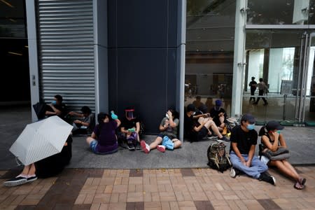 Exhausted demonstrators sit down on the pavement during a protest in Hong Kong