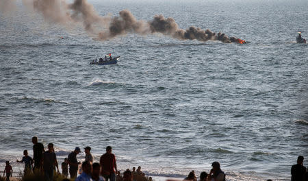 Palestinian demonstrators sail with boats towards the maritime border with Israel as smoke rises from a burning tire during a protest calling for lifting the Israeli blockade on Gaza, at the sea off the coast of the northern Gaza Strip September 17, 2018. REUTERS/Mohammed Salem
