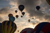 <p>Hot air balloons are inflated and take to the skies as they participate in the mass assent at sunrise in the main arena on the second day of the Bristol International Balloon Fiesta on August 11, 2017 in Bristol, England. (Photo: Matt Cardy/Getty Images) </p>