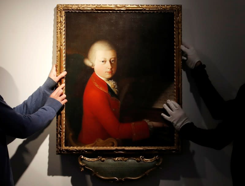 Workers install a portrait due to be sold at auction by Christie's in Paris which depicts composer Wolfgang Amadeus Mozart