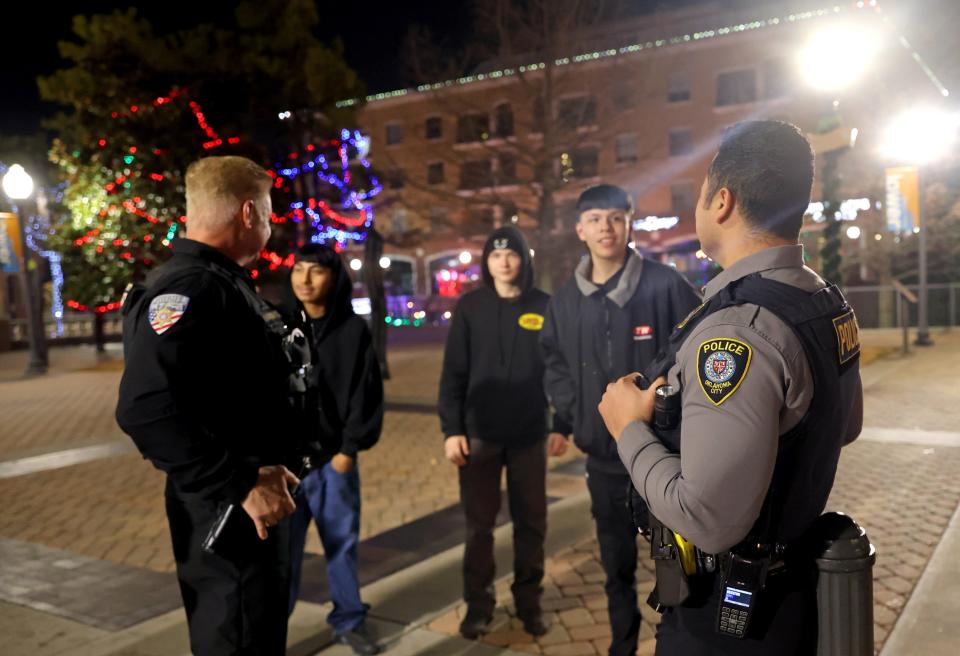 Sgt. Ivan Venegas, right, and Oklahoma County's Aaron Brilbeck inform youths on De. 22 of the curfew in Bricktown in Oklahoma City.