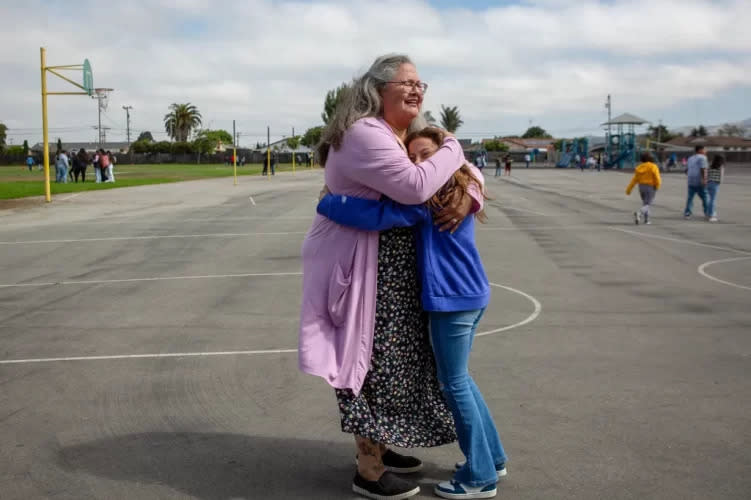 Catalina Cisneros, secretary at Loma Vista Elementary School, gets a hug from a student on the first day of school in Salinas on Aug. 8. (Semantha Norris/CalMatters)