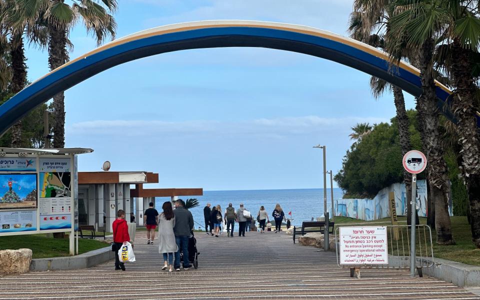 People walking on a boardwalk with a blue sea behind