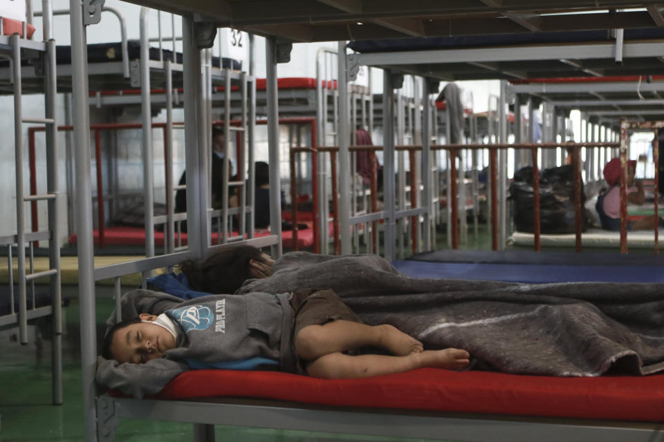 A mother and child sleep in a cot at the Kiki Romero Sports Complex after they were deported from the U.S., in Ciudad Juarez, Mexico, Wednesday, April 21, 2021. Mexico said it is planning to set up 17 shelters for underage migrants along the country's southern border, as well as some along the northern border with the United States, amid a wave of child migrants coming from Central America. (AP Photo/Christian Chavez)