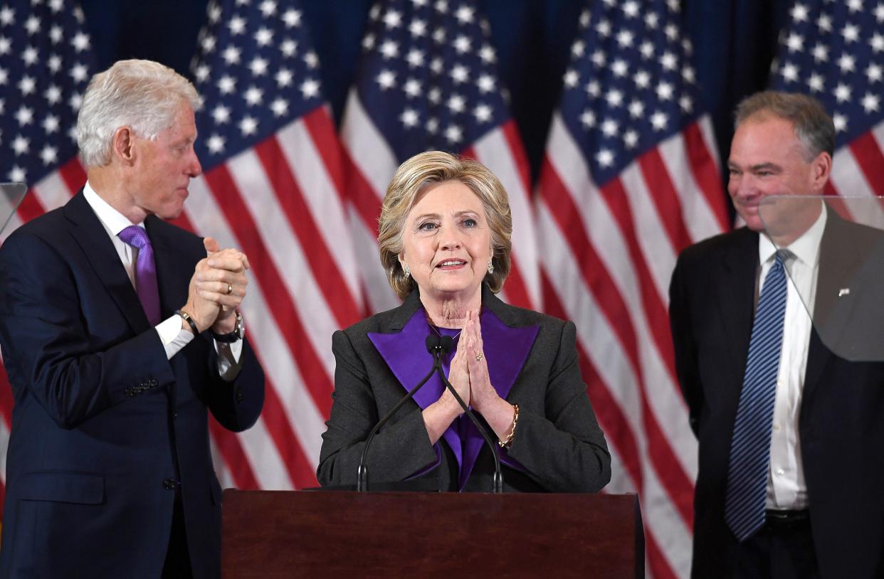 Hillary Clinton makes a concession speech standing at a podium in front of American flags next to former President Bill Clinton and Sen. Tim Kaine