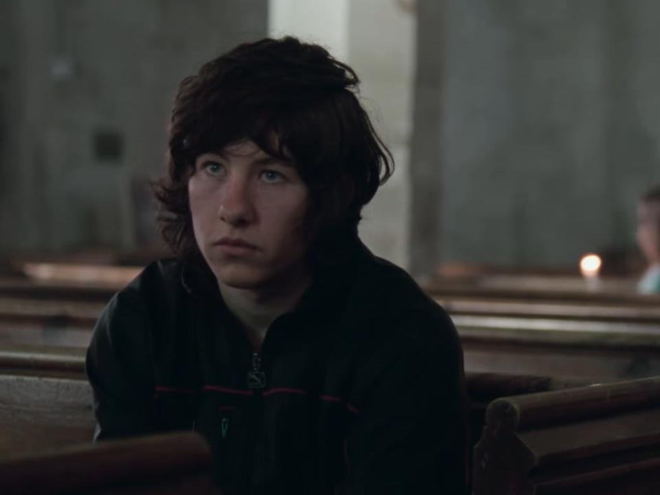 Barry Keoghan wearing a hoodie sitting in a church pew.