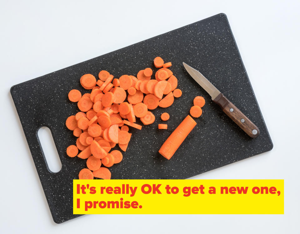 An overhead shot of a cutting board with a knife positioned next to a carrot that has been partially chopped into round slices