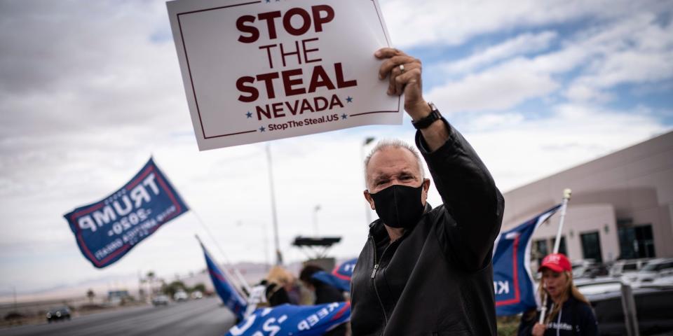 Supporters of President Donald Trump hold signs as they stand outside of the Clark County Elections Department in North Las Vegas, Nev. on Nov. 7, 2020