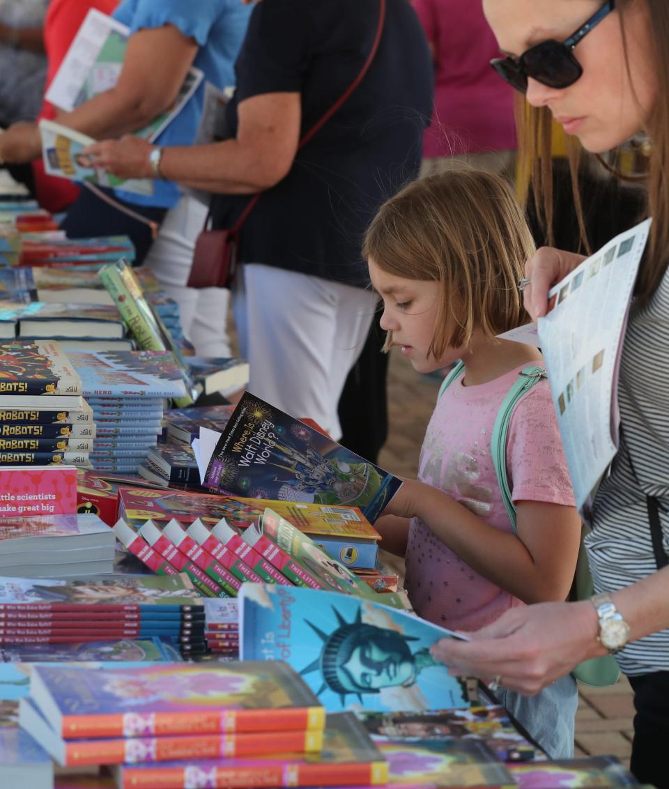 Danica Waples, 7 of Lehigh, digs into her book right at the table at the 2019 Southwest Florida Reading Festival. Over 5,000 books were handed out to the children and teens, as well as authors talking about their books and signing autographs.
