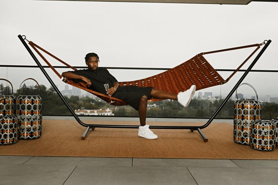 A person lies on a hammock drinking Champagne.