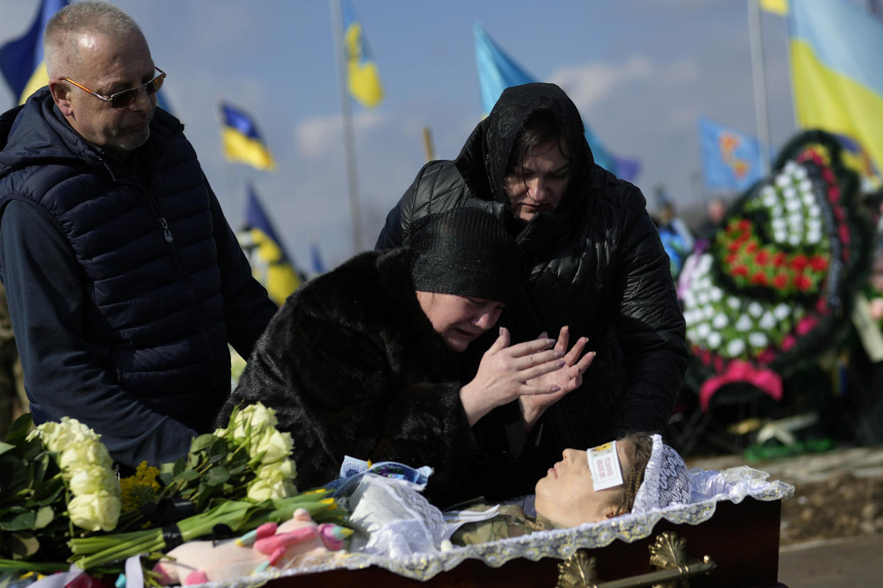Olena Rikhlitska, second right, and a young girl mourn at the open coffin of Yana Rikhlitska.