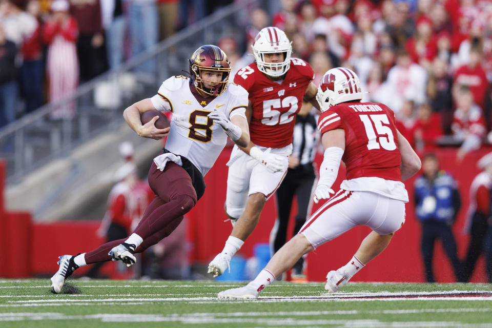 Nov 26, 2022; Madison, Wisconsin, USA; Minnesota Golden Gophers quarterback Athan Kaliakmanis (8) rushes with the football as Wisconsin Badgers safety John Torchio (15) defends during the second quarter at Camp Randall Stadium. Mandatory Credit: Jeff Hanisch-USA TODAY Sports