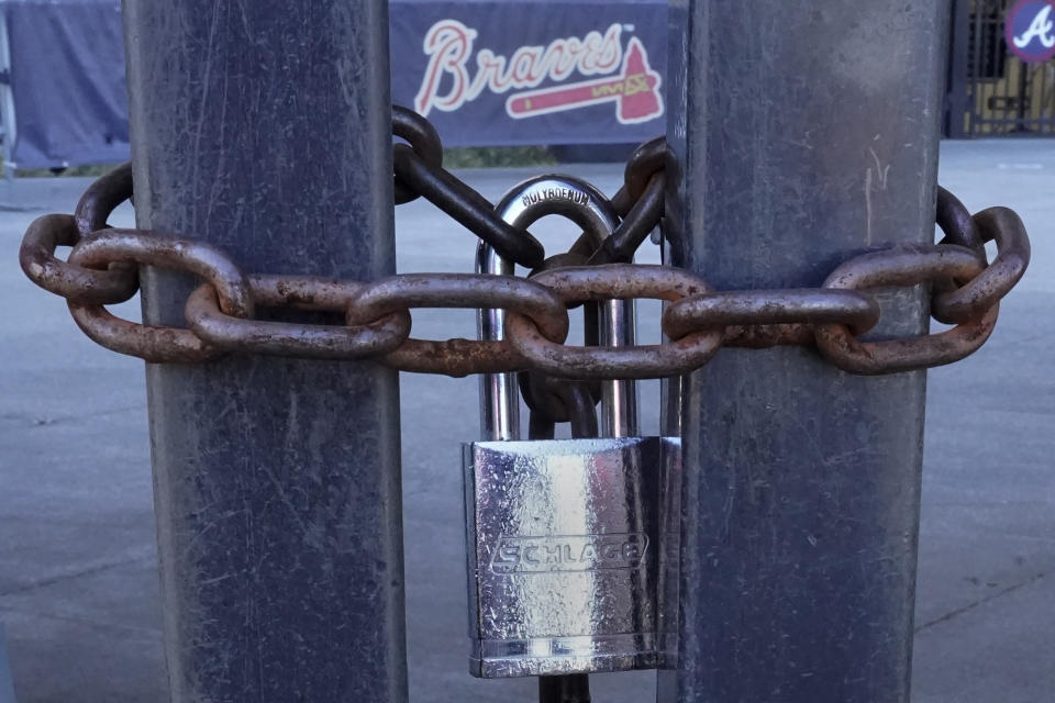 Locked gates are shown at Truist Park, home of the Atlanta Braves baseball team, Wednesday, March 2, 2022, in Atlanta. With owners and players unable to agree on a labor contract to replace the collective bargaining agreement that expired Dec. 1, baseball commissioner Rob Manfred followed through with his threat on Tuesday and canceled the first two series for each of the 30 major league teams. (AP Photo/John Bazemore)