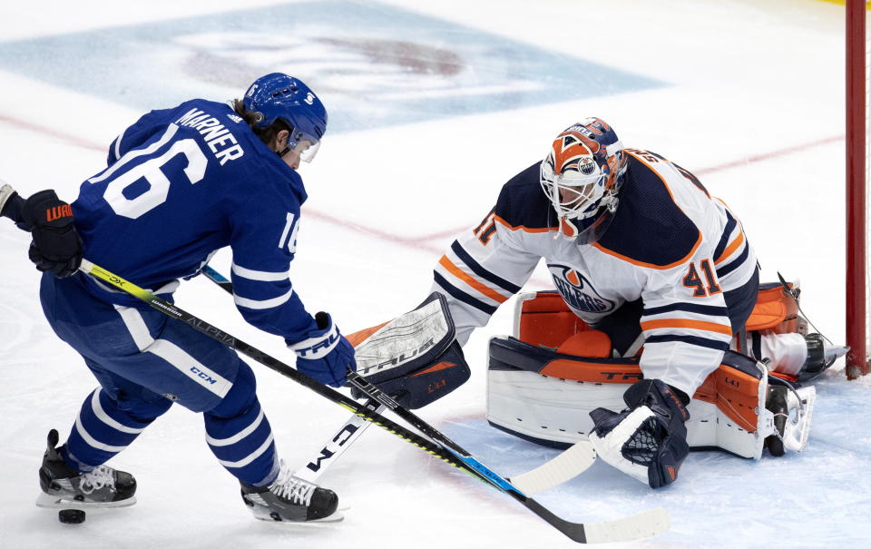 Edmonton Oilers goaltender Mike Smith (41) pokes the puck away from Toronto Maple Leafs center Mitchell Marner (16) during second-period NHL hockey game action in Toronto, Saturday, March 27, 2021. (Frank Gunn/The Canadian Press via AP)