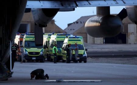 A man prays as Egyptian soldiers and rescue crews wait to transfer the bodies of victims of a plane which crashed in Sinai, from a civil police helicopter to an ambulance at Kabrit airport in Suez, east of Cairo, Egypt, October 31, 2015. REUTERS/Stringer