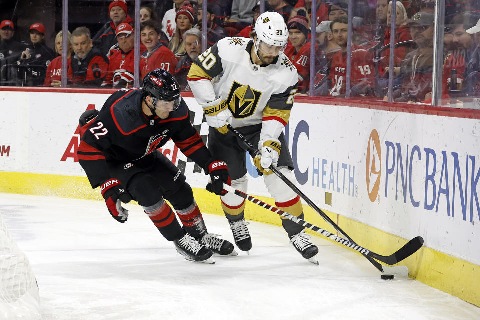 Carolina Hurricanes' Brett Pesce (22) battles for the puck with Vegas Golden Knights' Chandler Stephenson (20) during the first period of an NHL hockey game in Raleigh, N.C., Tuesday, Dec. 19, 2023. (AP Photo/Karl B DeBlaker)