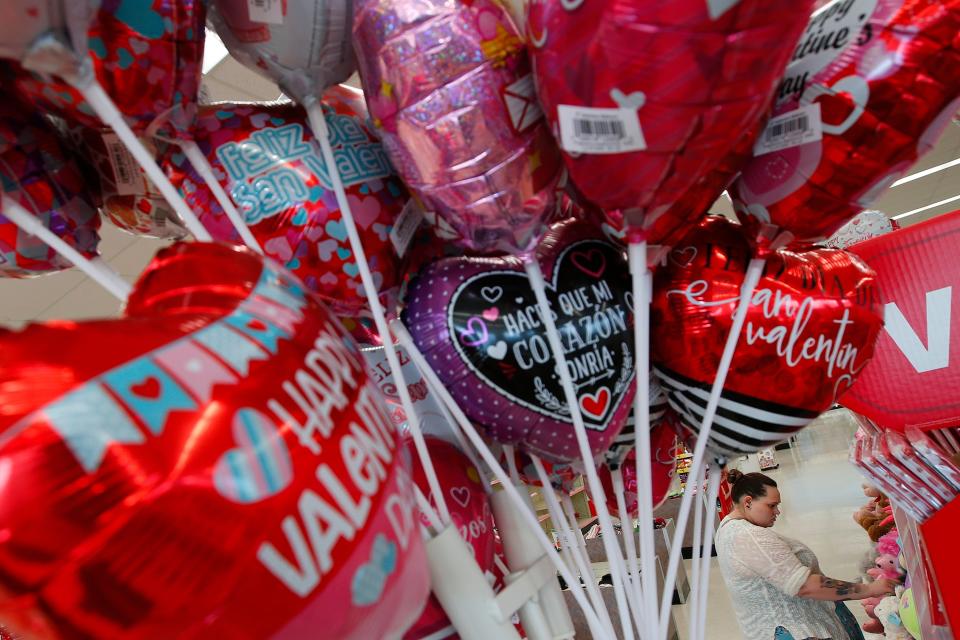 Colorful Valentine's Day balloons are seen in the foreground as a woman picks some stuffed animal gifts at Walgreen's in New Bedford, Massachusetts.