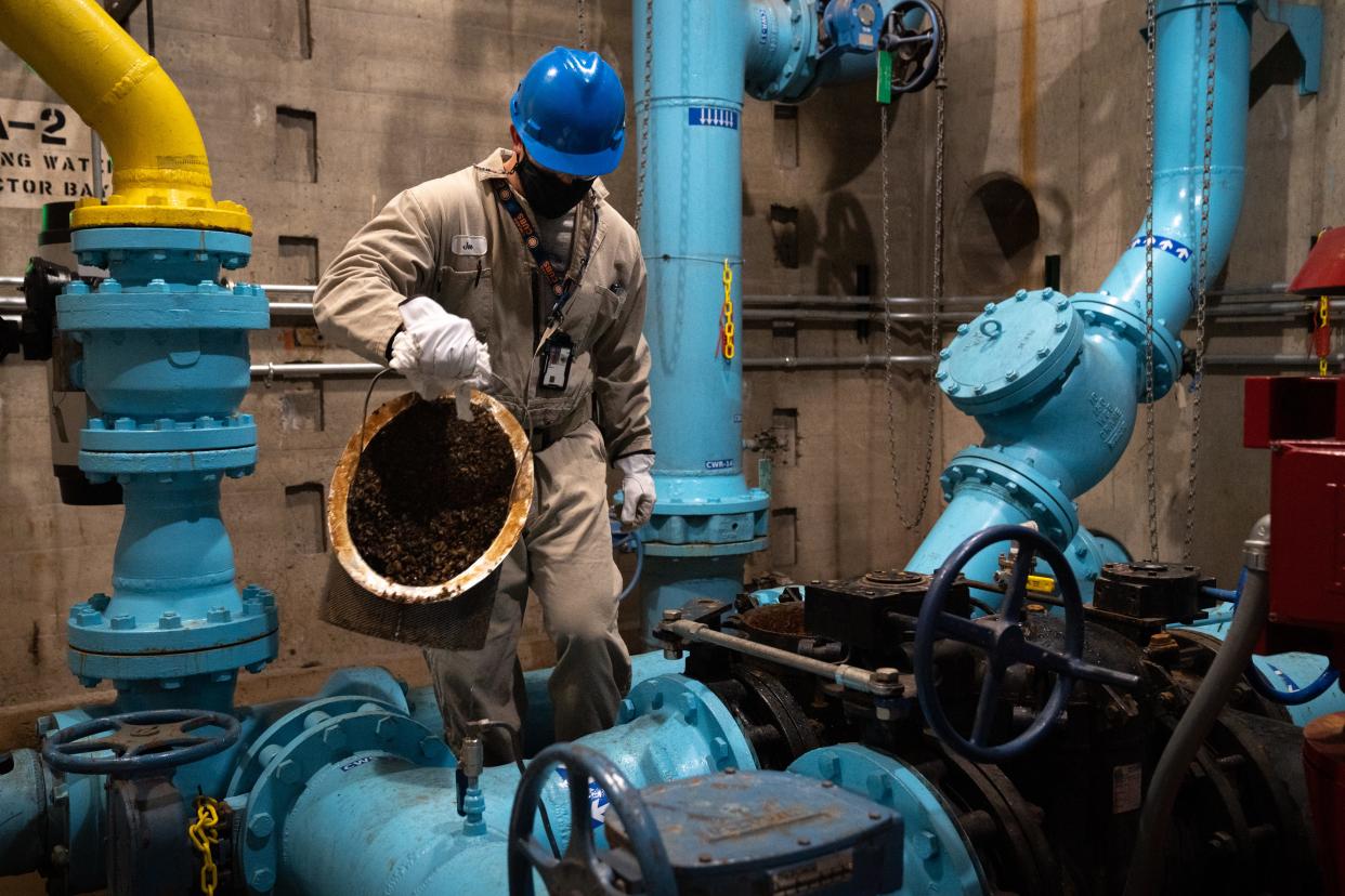 Joe Ford cleans mussels from a basket in the cooling water eductor bay on Feb. 16, 2022, at Hoover Dam on the Arizona/Nevada border.