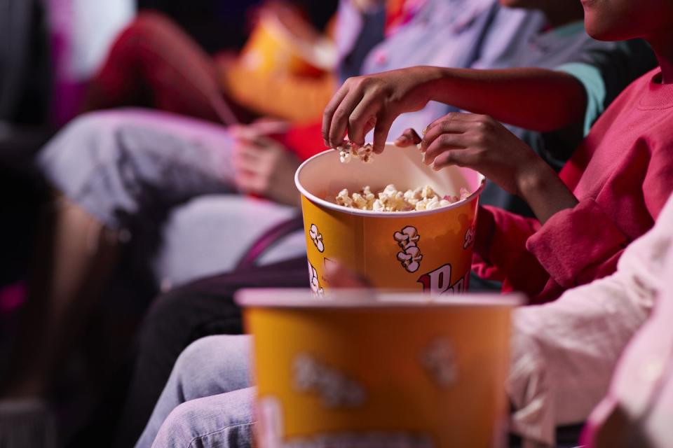 4th of july activities people eating out of a box of popcorn at the movies