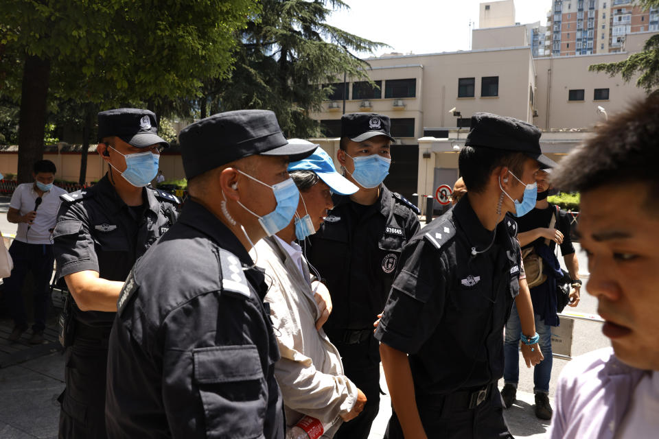 Chinese SWAT police officers escort away a man who tried to show protest slogans on his shirt outside the former United States Consulate in Chengdu in southwest China's Sichuan province on Monday, July 27, 2020. Chinese authorities took control of the former U.S. consulate in the southwestern Chinese city of Chengdu on Monday after it was ordered closed in retaliation for a U.S. order to vacate the Chinese Consulate in Houston. (AP Photo/Ng Han Guan)