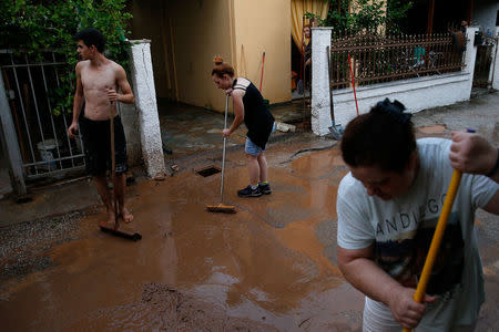 Locals remove mud from the entrance of a house, following flash floods which hit the town of Magoula, Greece, June 27, 2018. REUTERS/Costas Baltas