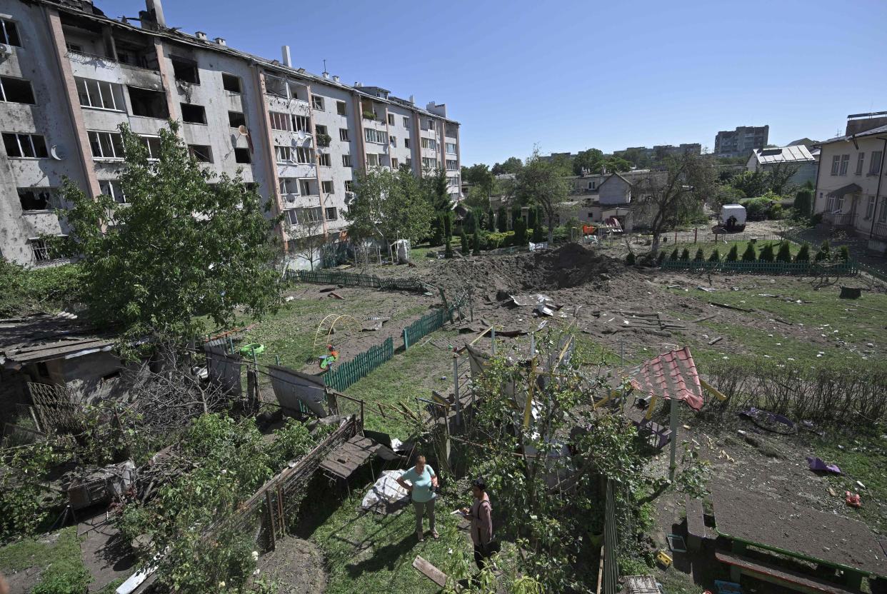 Local residents look at the crater of missile that fell between residential buildings and a kindergarten in the city of Lviv (AFP via Getty Images)