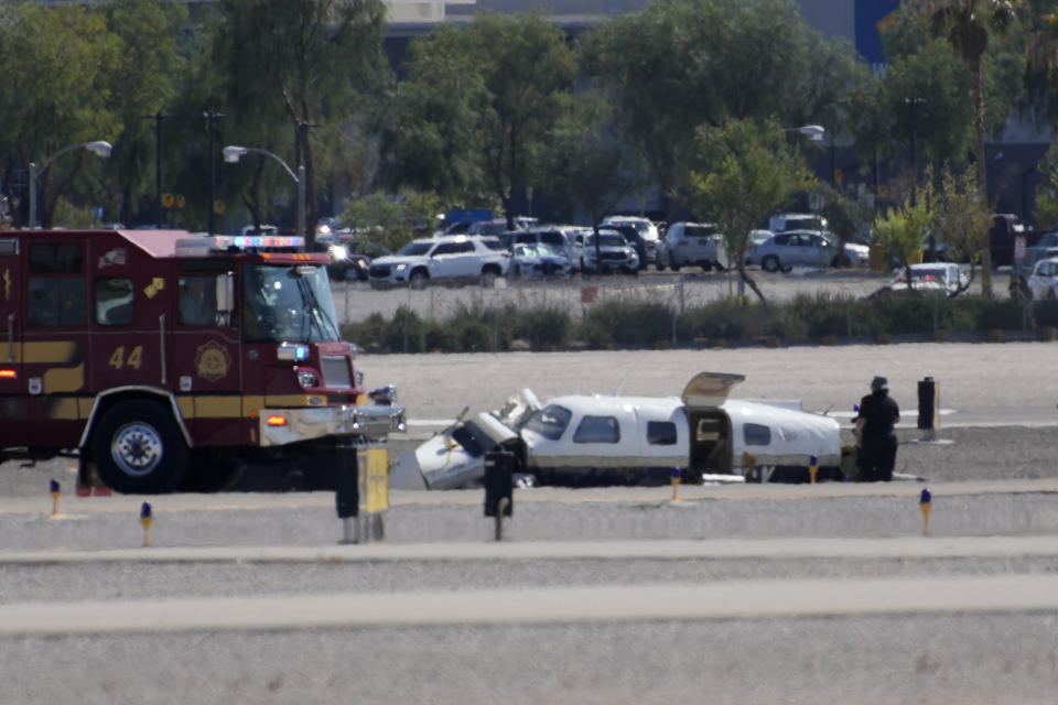 Officials investigate the wreckage of a plane at the site of a fatal crash at the North Las Vegas Airport, Sunday, July 17, 2022, in North Las Vegas, Nev. Authorities say several people are dead after two small planes collided at North Las Vegas Airport. (AP Photo/John Locher)