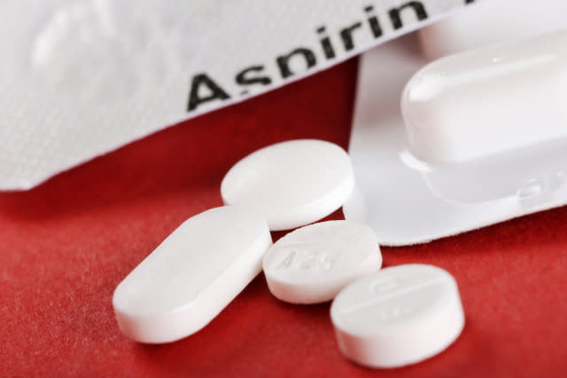 Close-up of four white tablets with aspirin container