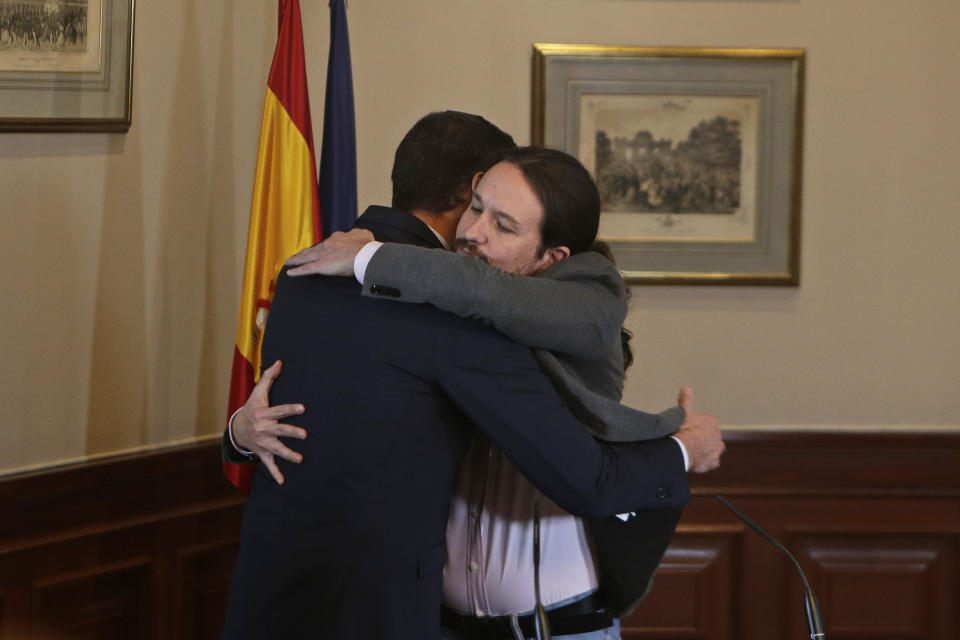 Spain's caretaker Prime Minister Pedro Sanchez, left, and Podemos party leader Pablo Iglesias hug after signing an agreement at the parliament in Madrid, Spain, Tuesday, Nov. 12, 2019.The leaders of Spain's Socialist party and the left-wing United We Can (Podemos) party say they have reached a preliminary agreement toward forming a coalition government. But the deal announced Tuesday won't provide enough votes in parliament for the Socialists, who won a general election, to take office without the support of other parties. (AP Photo/Paul White)