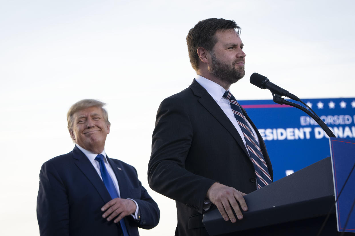 Former President Donald Trump mugs for the crowd as J.D. Vance takes the microphone.