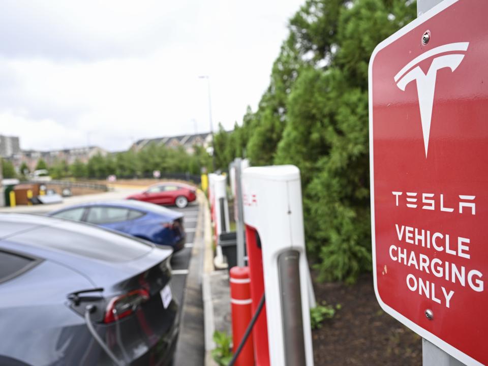 Several Tesla vehicles charge next to a sign that says "Tesla vehicle charging only"