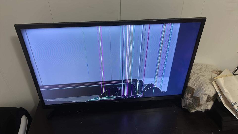 A television screen with visible cracks and multicolored vertical lines, indicating damage