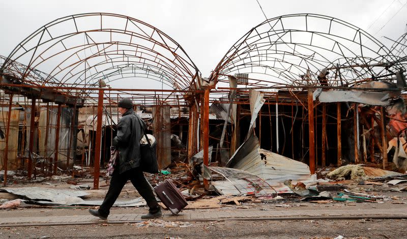 FILE PHOTO: A man walks past damaged kiosks in Mariupol