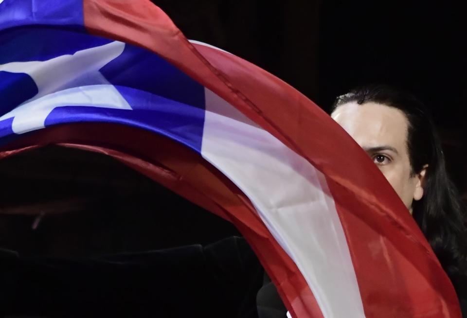 In this Jan. 11, 2019 photo, Lin-Manuel Miranda, composer and creator of the award-winning Broadway musical, Hamilton, proudly waves a Puerto Rican flag after receiving a standing ovation at the end of the play's premiere held at the Santurce Fine Arts Center, in San Juan, Puerto Rico. The musical is set to run for two weeks and will raise money for local arts programs. (AP Photo/Carlos Giusti)