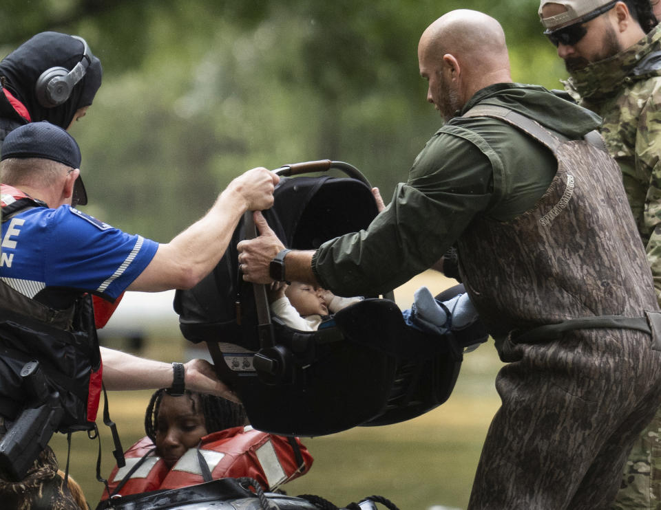 A child in a car seat is taken out of a boat as residents are evacuated by boat from their homes by Montgomery County Sheriff's Office deputies, Friday, May 3, 2024, in Conroe, Texas. Torrential rain is inundating southeastern Texas, forcing schools to cancel classes and closing numerous highways around Houston. (Jason Fochtman/Houston Chronicle via AP)