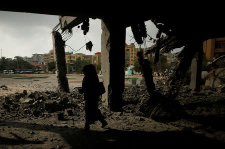 A Palestinian woman passes a building that was destroyed by Israeli air strikes in Gaza City July 15, 2018. REUTERS/Suhaib Salem