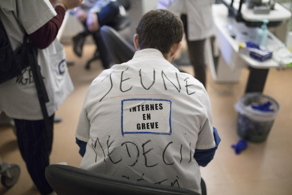 In this photo taken on Dec.16, 2019, a medical intern wears a sticker on his work clothes that reads "interns on strike" in the Hospital Nord in Marseille, southern France. In a hospital in Marseille, student doctors are holding an exceptional, open-ended strike to demand a better future. France’s vaunted public hospital system is increasingly stretched to its limits after years of cost cuts, and the interns at La Timone - one of the country’s biggest hospitals - say their internships are failing to prepare them as medical professionals. Instead, the doctors-in-training are being used to fill the gaps. (AP Photo/Daniel Cole)