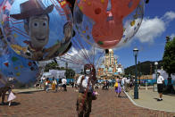 An employee wearing a face mask to prevent the spread of the new coronavirus, sells balloons at the Hong Kong Disneyland Thursday, June 18, 2020. In March, Hong Kong closed its borders to overseas countries, restricting visitors to those who have spent more than 14 days in mainland China, Macao and Taiwan. Tourist numbers plunged nearly 90%, with only about 3.5 million visitors arriving in the city between January and June this year. The city's airlines, hospitality and tourist industries – which had already took a hit from months of anti-government protests last year – took a second beating, with the government pledging $51.6 million in subsidies to help them stay afloat. (AP Photo/Kin Cheung)