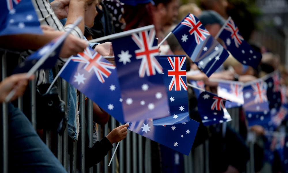 People wave Australian flags as they watch the Anzac Day parade in Sydney on 25 April 2017.